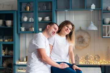 Christmas, portrait of a happy adorable couple celebrating Christmas at home, hugging and getting closer. Holiday and winter holiday of happy people. Interior of a kitchen decorated for the holiday.