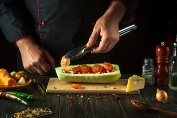 The chef prepares a stuffed zucchini boat on the kitchen table of the restaurant. Delicious lunch with national dish stuffed squash.