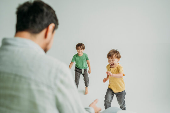 Man playing with happy children against white background