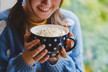 Happy girl holding mug of hot chocolate with whipped cream