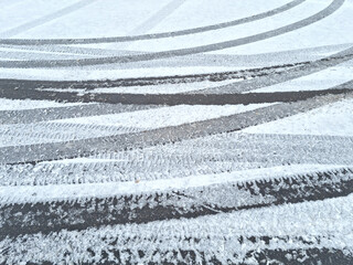 Dynamic car tread marks on the snow. Early winter. Energy and expression of movement. Black and white wheel print graphics