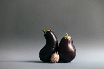 Eggplants and single gooseberry against gray background