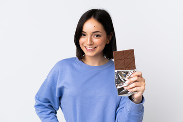 Young caucasian woman isolated on white background taking a chocolate tablet and happy