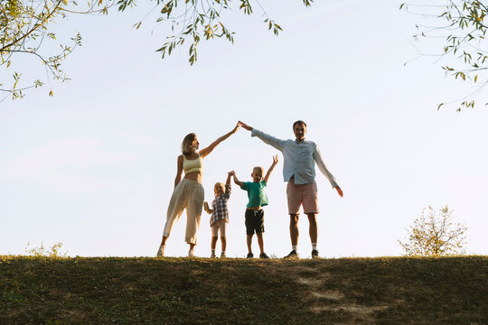 Parents and children standing with arms raised in park