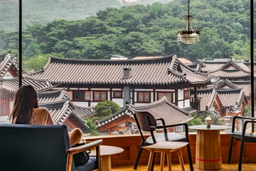 Afwasbaar fotobehang 대한민국 서울 은평구 은평한옥마을에 있는 카페에 앉아 있는 여자와 창문 밖으로 한옥마을이 보이는 풍경 © Yido
