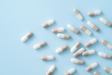 Taking medicine design concept, top view of capsule pills on blue table background.