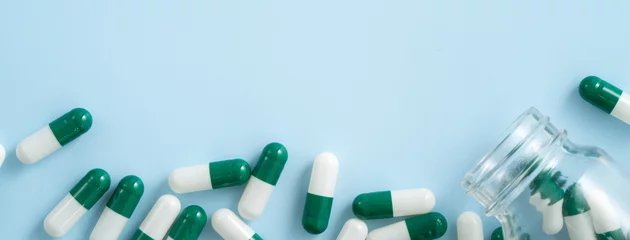 Keuken spatwand met foto Taking medicine design concept, top view of capsule pills on blue table background. © RomixImage