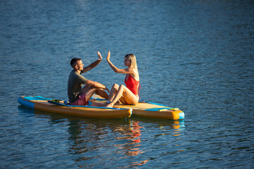 Young woman and sitting on sup board in the open ocean.