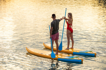 Man and woman with athletic body on surf board on river.