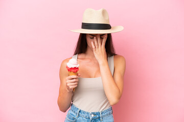 Young caucasian woman with a cornet ice cream isolated on pink background with tired and sick...
