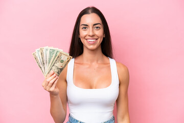 Young caucasian woman taking a lot of money isolated on pink background smiling a lot