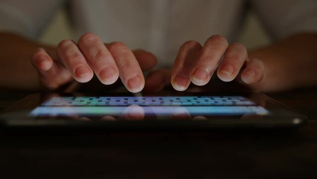 Woman typing text message on touch screen keyboard of tablet close-up.