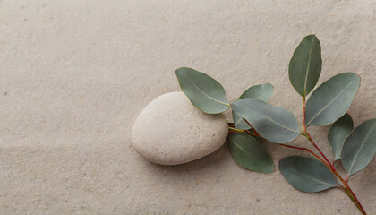 Fototapeta na wymiar serenity eucalyptus branch and a pebble rock on sand for background template with empty space for copy or product