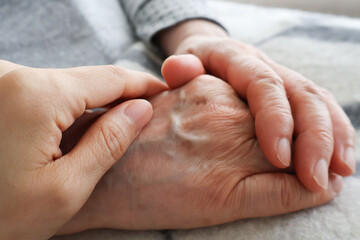 高齢女性の手を握る女性の手
