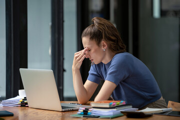 Businesswoman sitting in the office is stressed, working hard, feeling stressed and dizzy from...