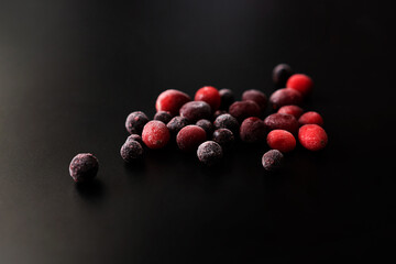 frozen cranberries and black currants on a black background