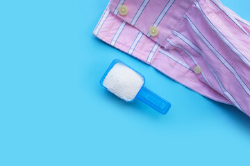 Detergent powder in measuring spoon with shirt. Laundry concept.