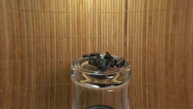 Shungite on a jar against a brown raffia background