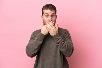 Young caucasian man isolated on pink background covering mouth with hands
