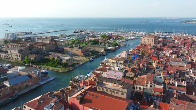 Aerial flight over the old port city of Chioggia with red roofs, narrow streets and lots of canals.