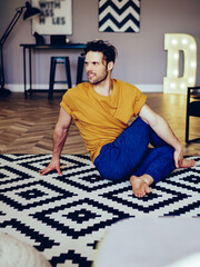 Experienced sportsman warming up before workout at home interior of apartment