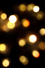 Obraz premium festive New Year's bokeh of warm yellow color, blurred on a dark background