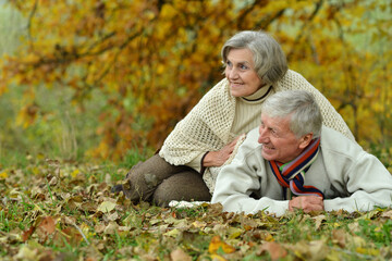 Naklejka na ściany i meble Portrait of a mature couple lying on the autumn leaves