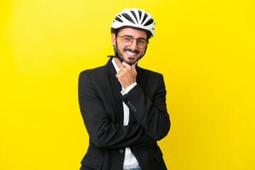 Business caucasian man with a bike helmet isolated on yellow background with glasses and smiling