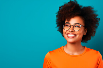  a young afroamerican woman with glasses wear a orange top on blue background - obrazy, fototapety, plakaty