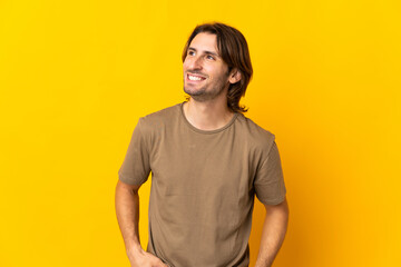 Young handsome man isolated on yellow background looking to the side and smiling