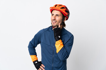 Young cyclist man isolated on white background thinking an idea while looking up