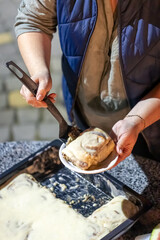 A woman puts cinnabon on a plate at a family party.