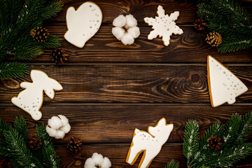 Frame of white Christmas cookies with fir tree branches. New Year background