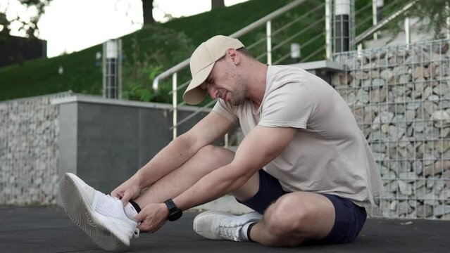 A man feels acute pain in his ankle joint and massages his painful leg during an evening walk. Sports and injury concept.