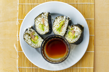 Close-up top view of home made sushi with rice, avocado and salmon on white plate. Photo taken October 30th, 2023, Zurich, Switzerland.