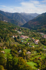 Panoramic view from above, from the throne to the valley in the mountains. A small village in the Alps. Colored houses, tiled roofs, a road and a river. Europe