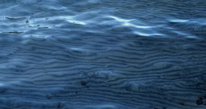 Seamless sand dunes under clear water surface with waves.