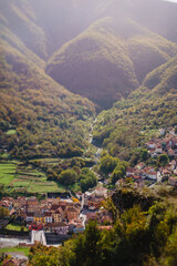 Fototapeta na wymiar Panoramic view from above, from the throne to the valley in the mountains. A small village in the Alps. Colored houses, tiled roofs, a road and a river. Europe. Italy