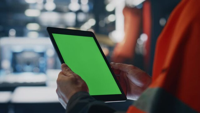 Specialist hands holding green screen tablet at manufacturing facility close up.