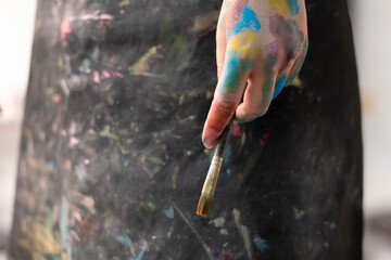 female artist in black apron holding a brush