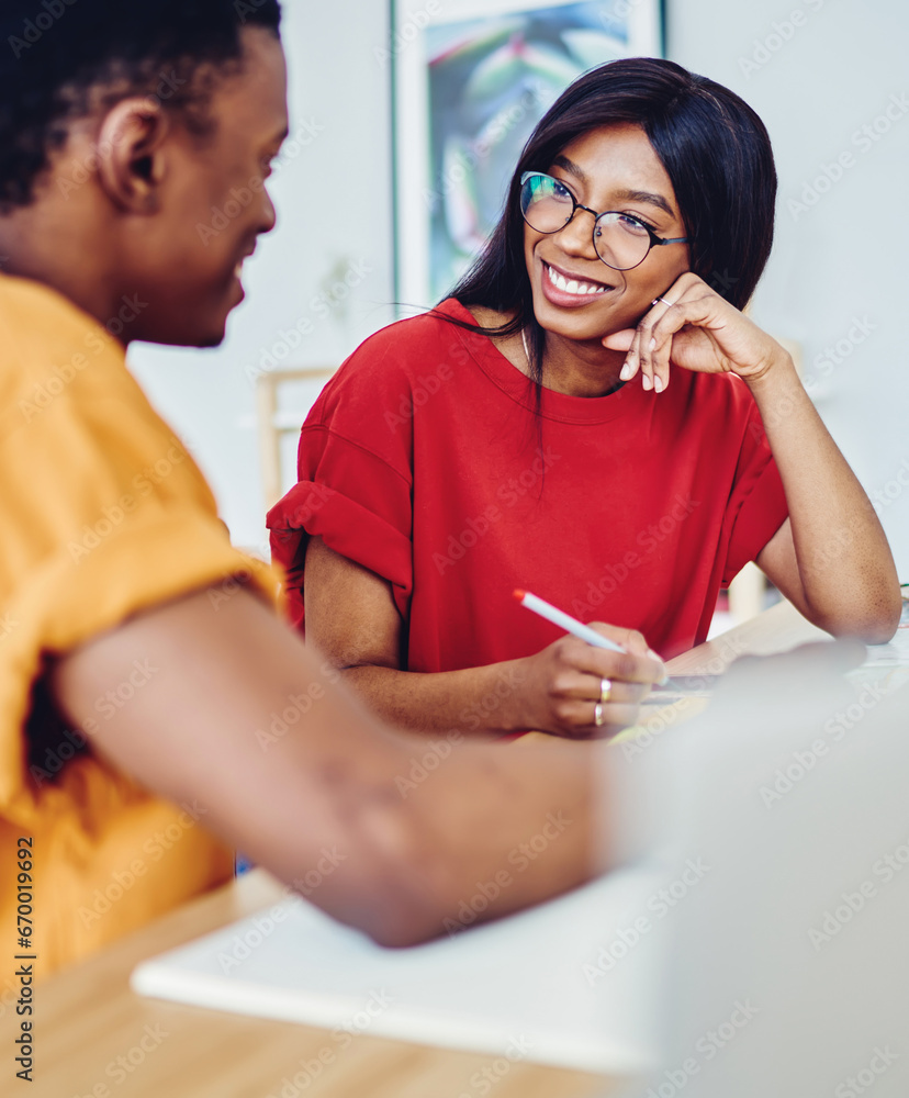 Poster smiling dark skinned woman having interview with male applicant ask questions and make notes
