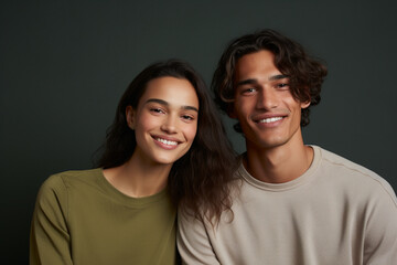 Middle shot of a couple of friends smiling and looking at the camera in a brown studio background