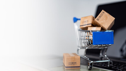 Shopping cart and product boxes on laptop computer on white background and copy space. online shopping marketplace platform website E-commerce technology and online payment concepts