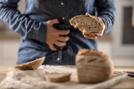 Woman can't eat bread and grain products because of gluten intolerance. A young celiac woman suffers from abdominal pain after eating fresh bread
