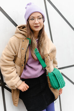Young woman wearing knit hat leaning on wall