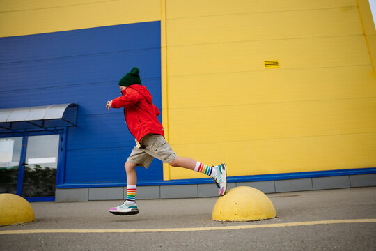 Boy running on bollards at street by building