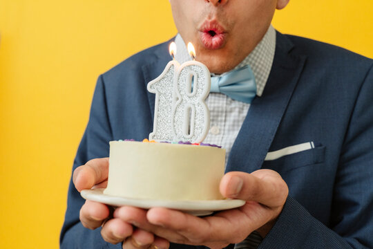 Man blowing 18th birthday candle on cake