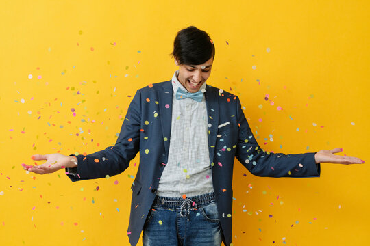 Happy Man Playing With Confetti Against Yellow Background