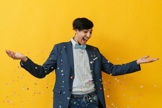 Cheerful man celebrating with confetti against yellow background
