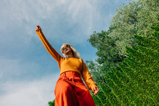 Woman with hand raised standing in garden